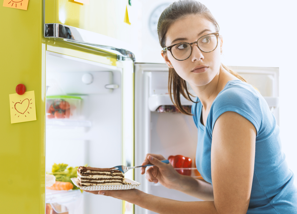 woman sneaking cake from a fridge - stop falling off the diet wagon - heikeyates.com