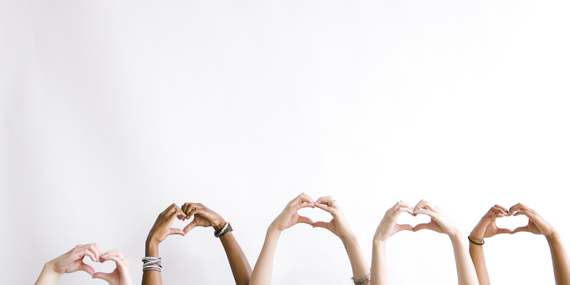 women holding up their hands in the shape of hearts