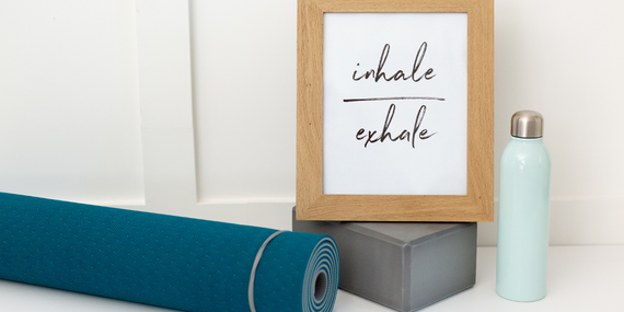 yoga mat, yoga block, water bottle and a framed picture that says inhale exhale