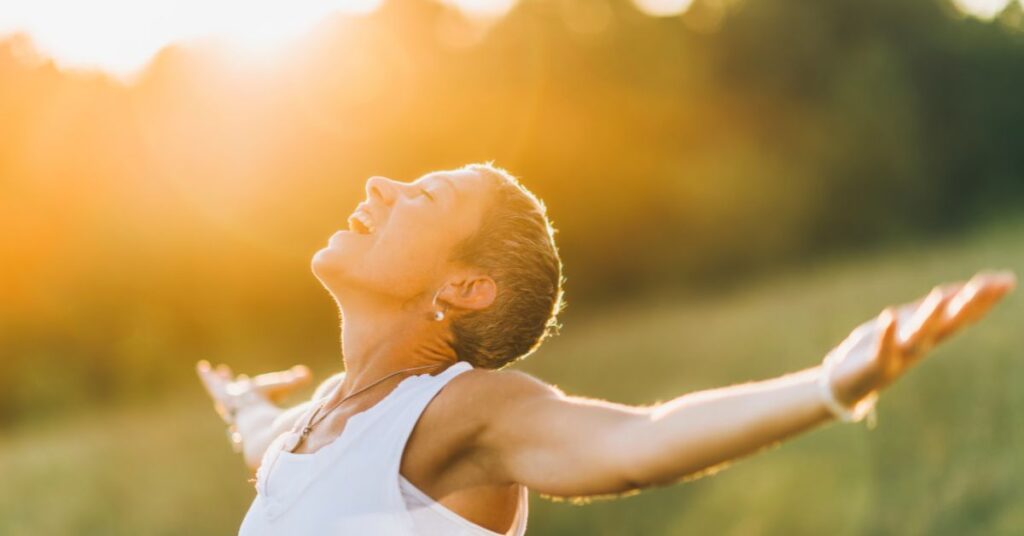5 Habits That Can Help You Transform Your Midlife - woman smiling and embracing the sun