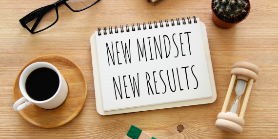 a sign saying: new mindset, new results next to an hour glass and coffee cup. Why a “Midlife Crisis” Isn’t the End—It’s Your New Beginning