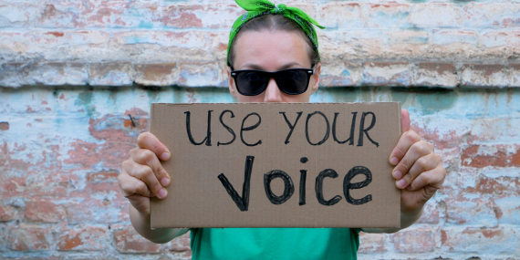 woman holding a sign saying use your voice in midlife