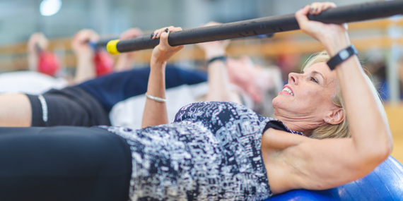 woman pushing a bar up prevent to midlife weight gain