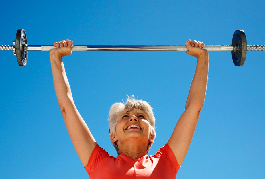 Muscle Loss in Midlife: What Women Need to Know Now , woman pushing weighted bar overhead in midlife