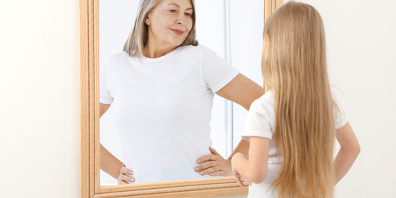 Building Consistency in Midlife: Why Speaking Up Still Leaves Women Feeling Small. Woman in the mirror looking at the young girl she was.