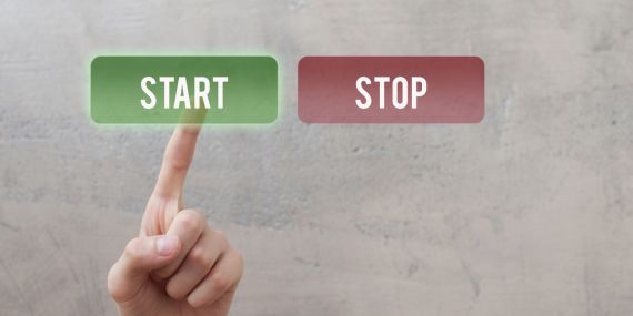 Why Women in Midlife Keep Resetting Their Goals. a wall with a start and stop sign the finger pushes the start button. 