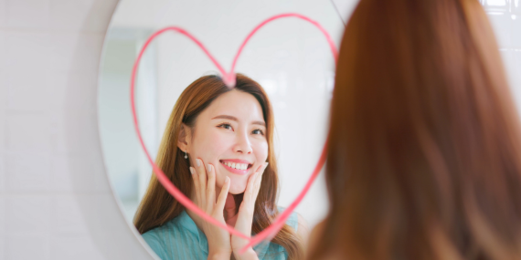 Midlife Body Disconnect: Why You Don't Feel Like Yourself Anymore. woman smiling into a mirror with a heart on it.