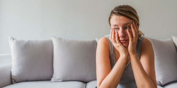 Midlife Body Disconnect: Why You Don't Feel Like Yourself Anymore. woman sitting on the couch feeling sad and disconnected