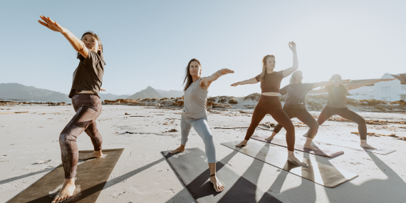 group of women outdoors working on a straight line yoga pose