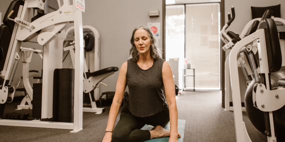 woman enjoying a yoga stretch in the gym as part of her midlife fitness