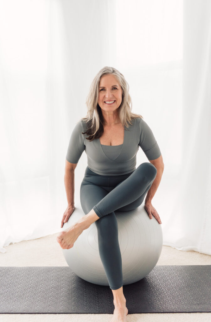 Heike Yates sitting on a ball teaching midlife fitness classes
